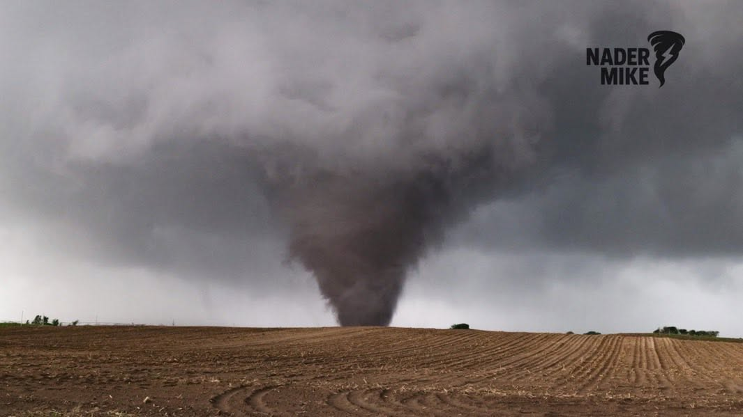 A large tornado extends from a supercell over an open field, photographed by NaderMike